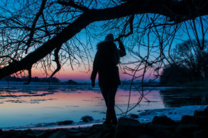 Silhouette of a Woman standing at a beach. Twilight evening mood at the frozen river Elbe in Geesthacht near Hamburg Silhouette of a Woman standing at a beach. Twilight evening mood at the frozen river Elbe in Geesthacht near Hamburg